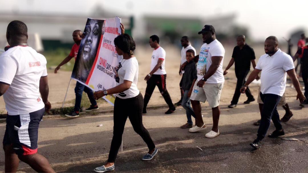The procession moves through the streets around the National Stadium with LASTMA officers facilitating safe passage. Members and supporters carry the DNKI banner as traffic is managed around the group.