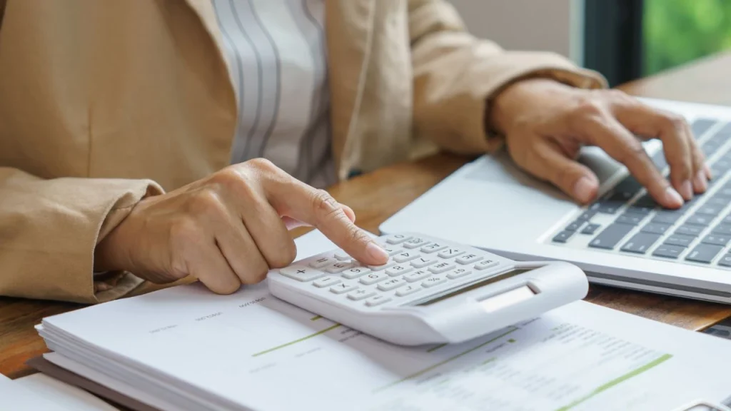 Who is watching the budget: a woman calculating a budget using a calculator and laptop.